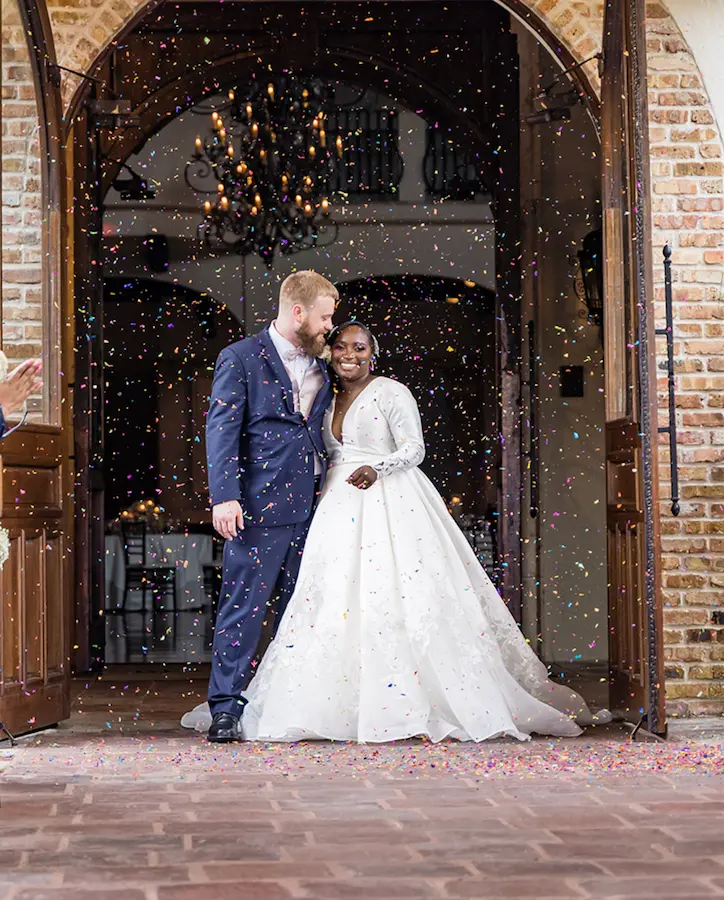Newlyweds walking through a confetti grand exit at their wedding