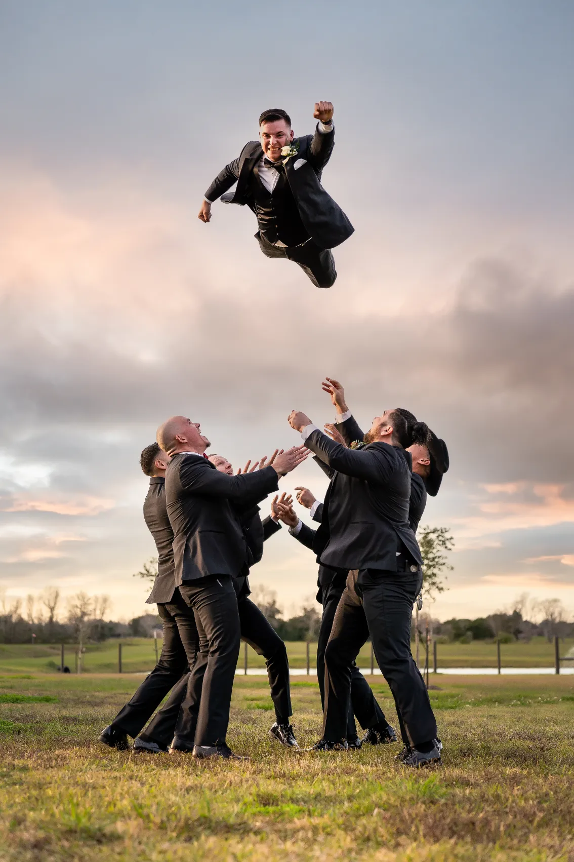 Groomsmen tossing the groom into the air during sunset wedding portraits